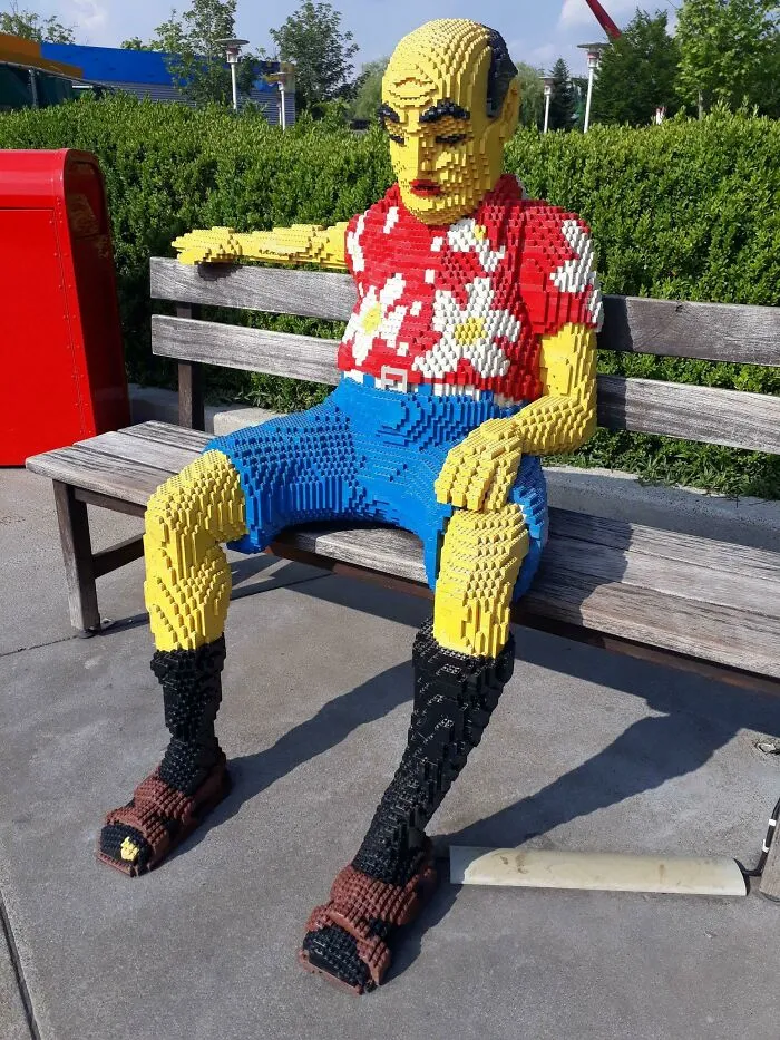 LEGO build of a seated figure wearing a red floral shirt and blue shorts, showcasing incredible LEGO art skills outdoors.