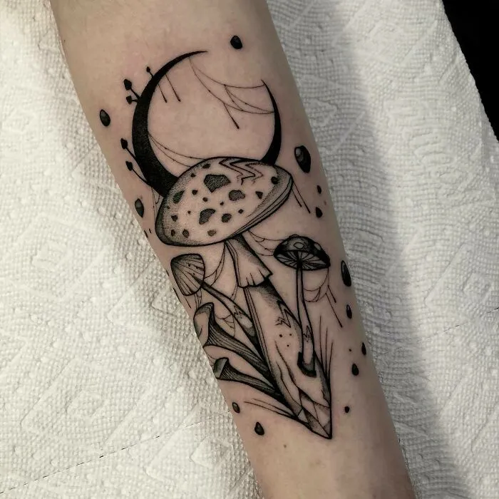 Trippy tattoo featuring mushrooms and a crescent moon on an arm.