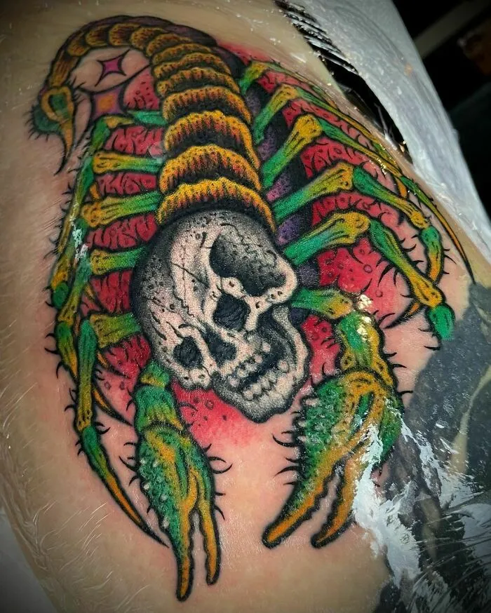 Colorful trippy tattoo of a scorpion with a skull on skin.