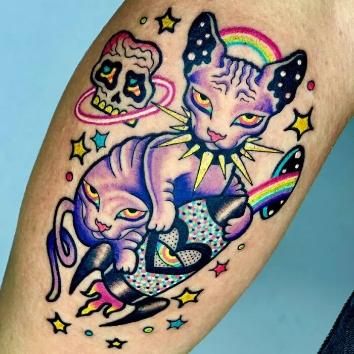 Colorful trippy Egyptian cat tattoo with a skull and rocket leg, featuring vibrant cosmic elements.