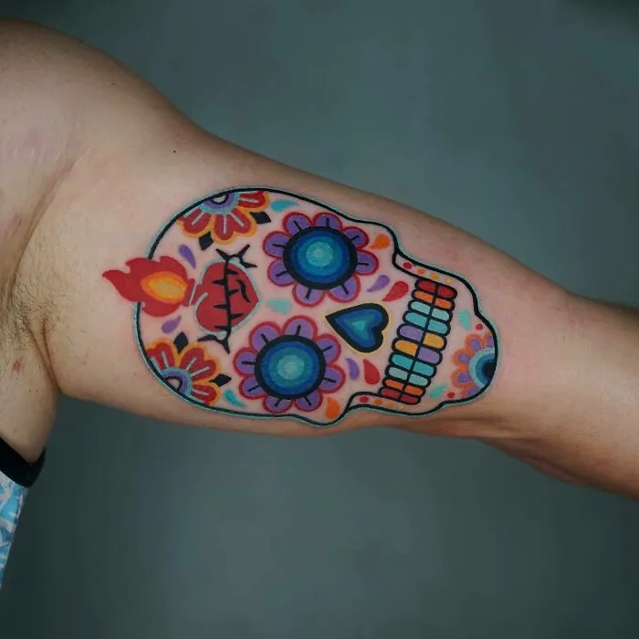 Colorful trippy tattoo of a sugar skull on arm, featuring vibrant designs and patterns.