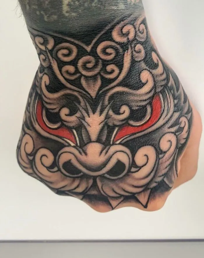 Trippy Foo Dog Japanese hand tattoo with intricate swirls and vibrant red accents.