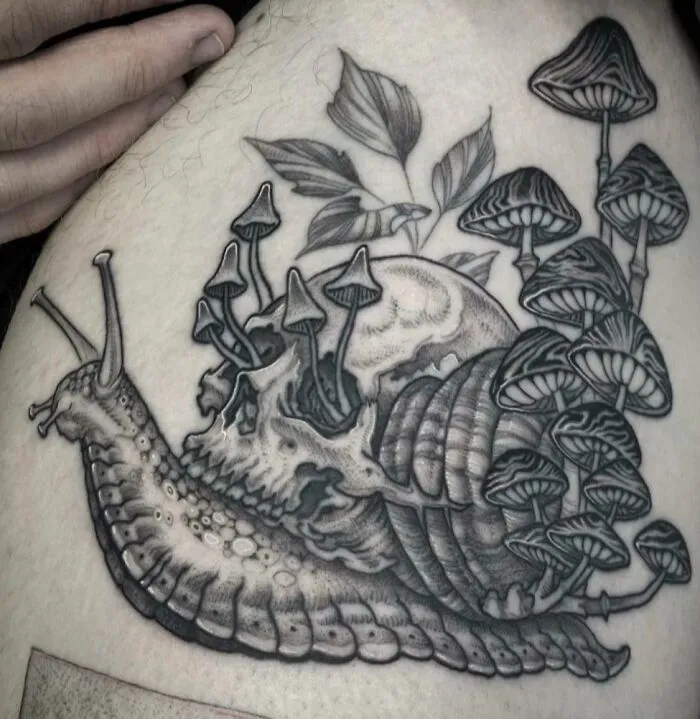 A trippy tattoo featuring a snail with a skull-like shell and mushrooms growing on its back.