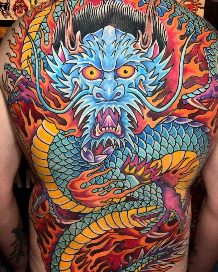 Colorful blue and red dragon tattoo covering entire back, exemplifying trippy tattoo ideas.