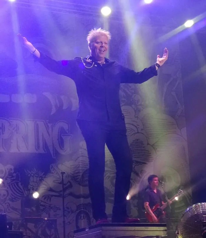 Performer on stage with arms outstretched, spotlight shining, representing smartest celebrities known for talent and intelligence.