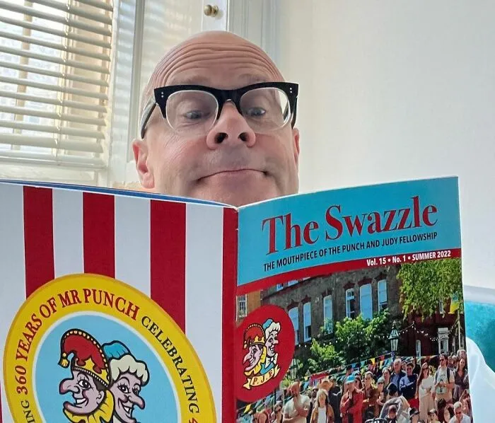 Bald man with glasses reading a magazine, representing the concept of smartest celebrities and intelligence.