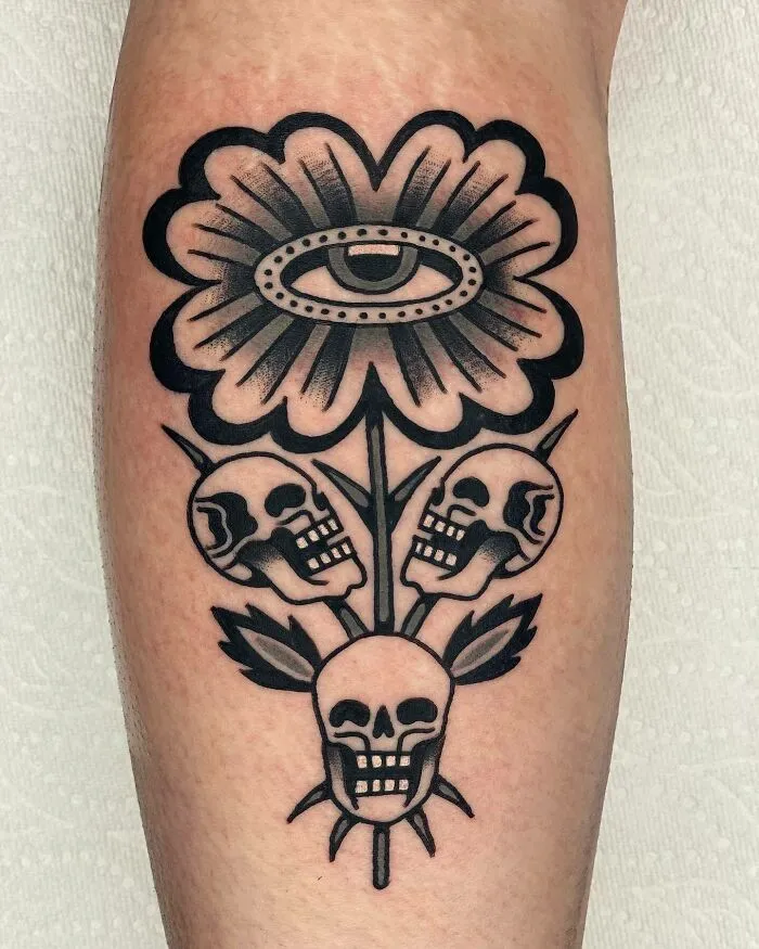 Trippy skulls and flower with eye tattoo on arm, featuring bold black ink design.