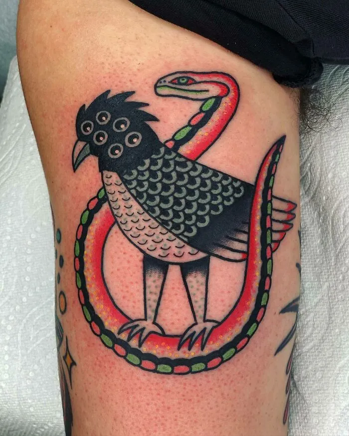 Psychedelic tattoo of a bird with multiple eyes entwined with a colorful snake on a person's arm.