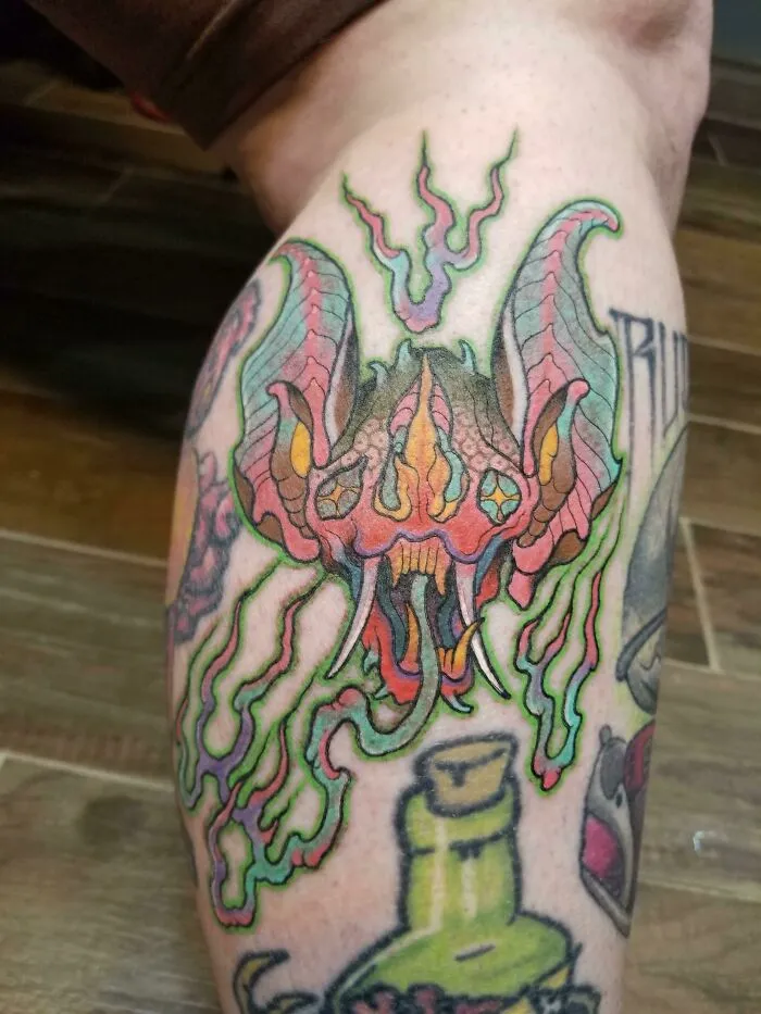Colorful trippy tattoo of a bat on a leg, featuring vibrant hues and psychedelic design elements.