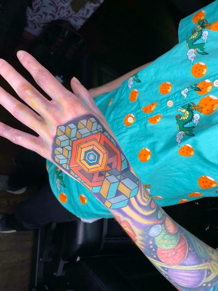 Colorful trippy tattoo with geometric design and vibrant patterns on an arm.