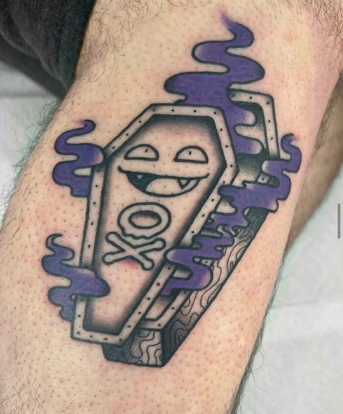 Trippy tattoo featuring a smiling coffin with purple smoke, blending geometric and cartoon elements on the skin.