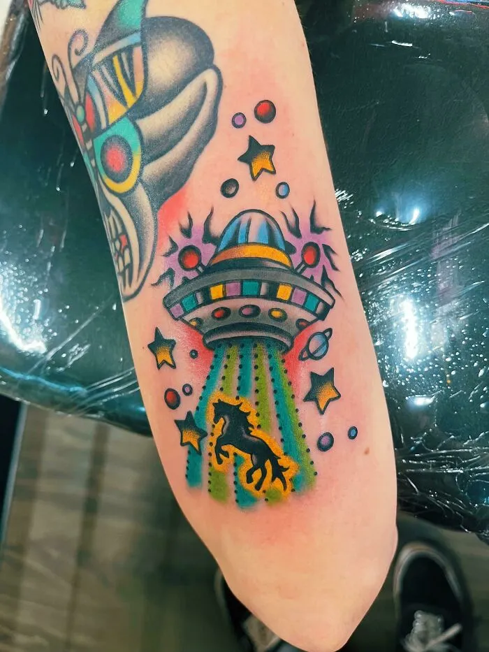 UFO-themed trippy tattoo with colorful beams and stars, showcasing a horse being abducted.