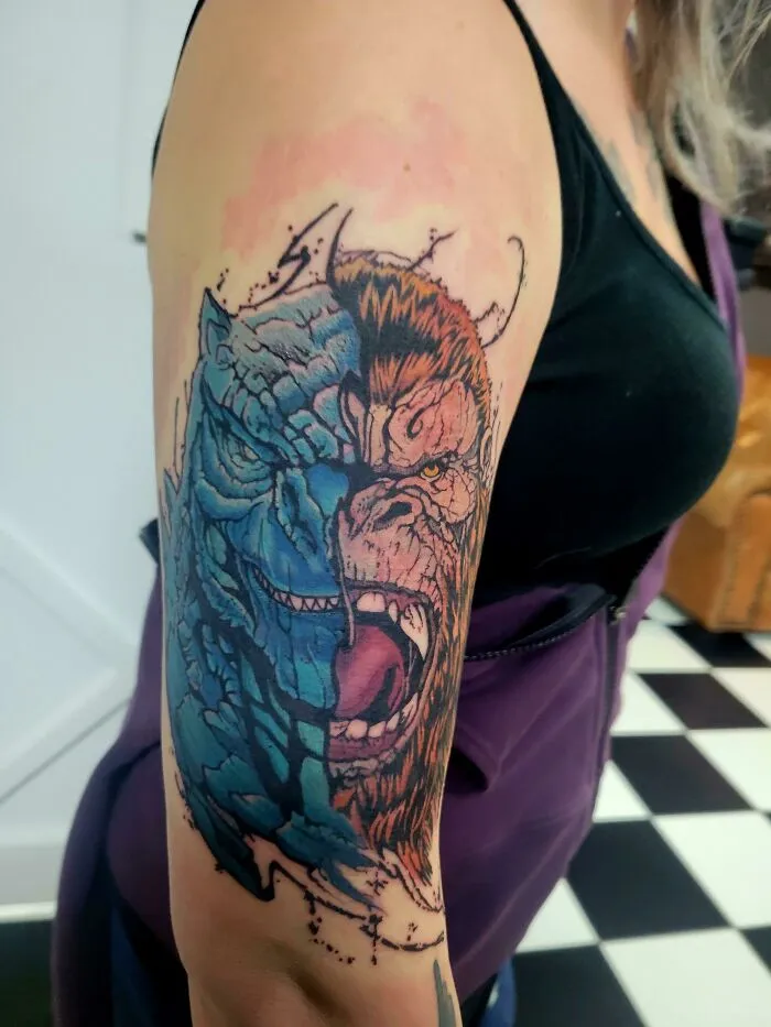 Close-up of a colorful, trippy tattoo on a woman's arm showcasing psychedelic art with a dual-faced creature design.
