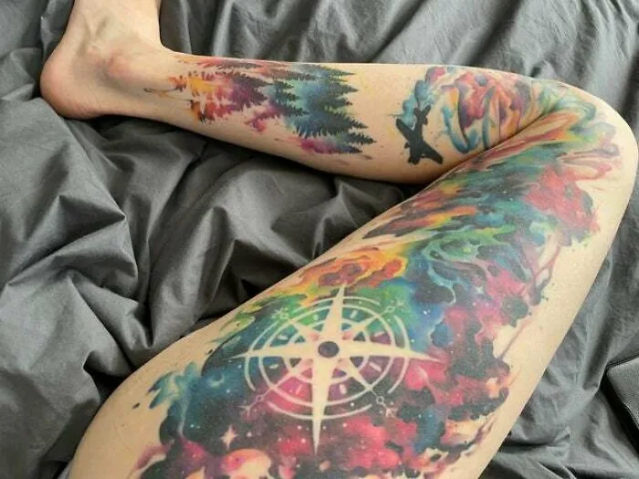 Colorful trippy tattoo with nature and compass design on a person's leg.