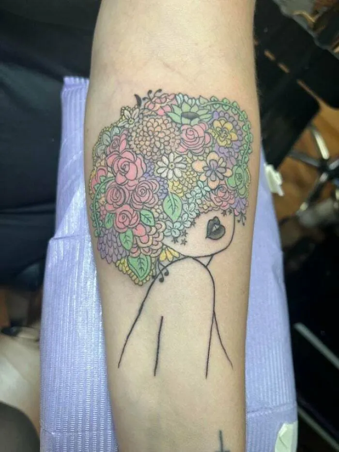 Vibrant trippy tattoo with floral hair design on forearm.