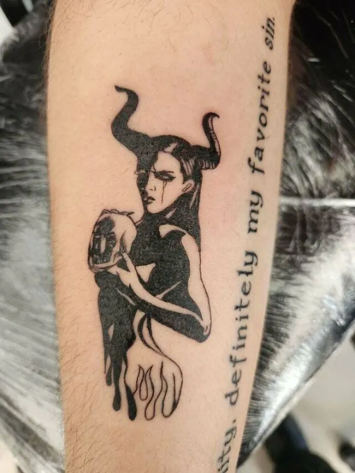 Psychedelic tattoo of a horned figure holding a skull, with text beside it.