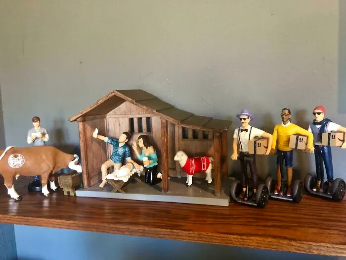 Humorous Christmas nativity scene with modern twist, featuring figurines on Segways and a cow with earbuds.