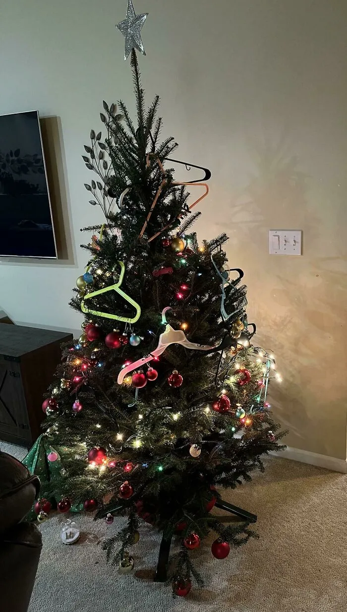 Christmas tree humorously decorated with hangers and colorful ornaments.