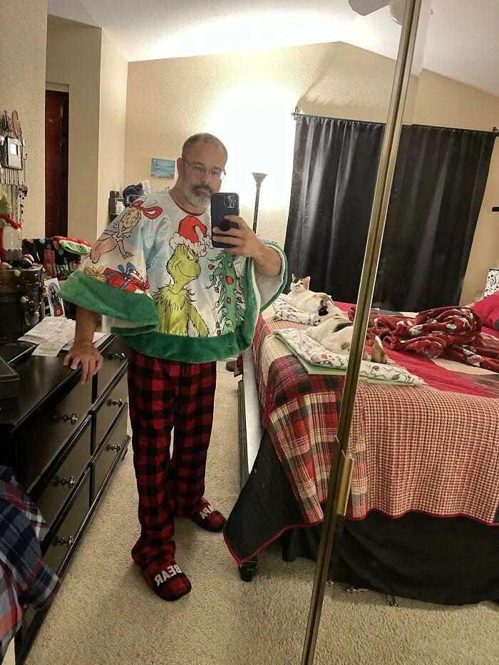 Man in a Grinch-themed towel and festive pajamas, capturing a humorous Christmas selfie.