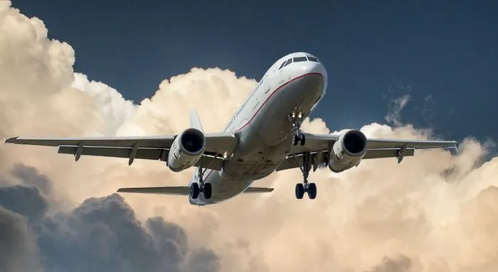 Airplane flying through cloudy sky, symbolizing New Year’s Eve travel and adventure.