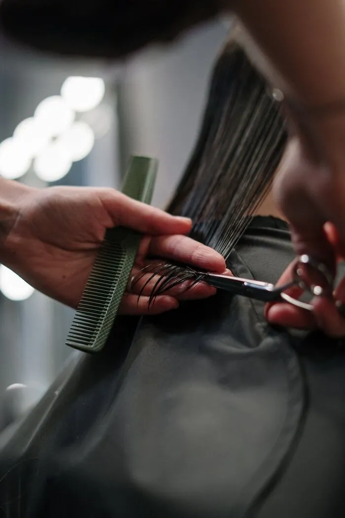 Hair being trimmed with scissors and a green comb, perfect for a New Year’s Eve makeover.