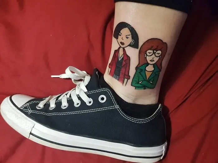 Cartoon tattoo inspired by animated shows on ankle next to a black sneaker.