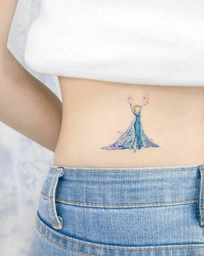 Cartoon tattoo on lower back featuring a character in a blue dress from an animated show.