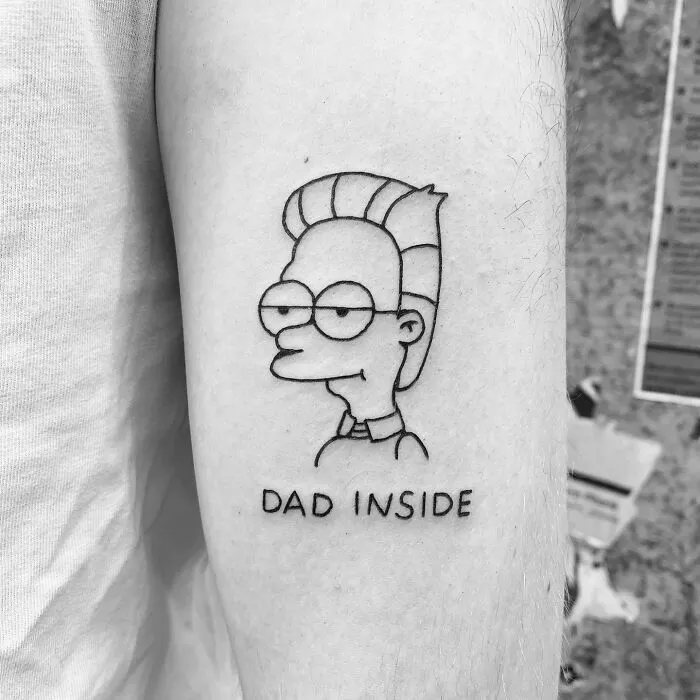 Cartoon tattoo of a Simpsons character with "Dead inside" inscription on arm, evoking nostalgia.