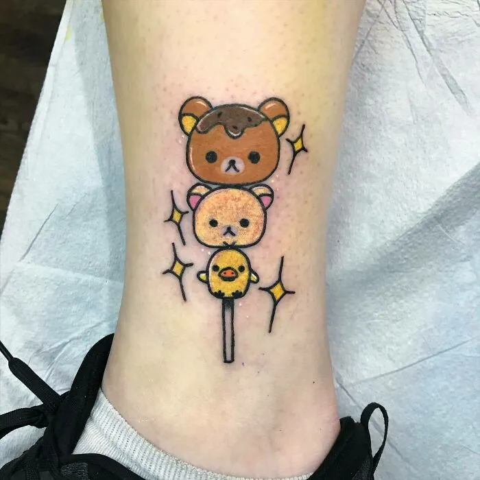 Cartoon tattoo featuring cute bears and a chick from animated shows, resembling a dango on a person's leg.