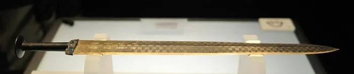Ancient sword artifact displayed in a museum exhibit, showcasing intricate designs and historical significance.
