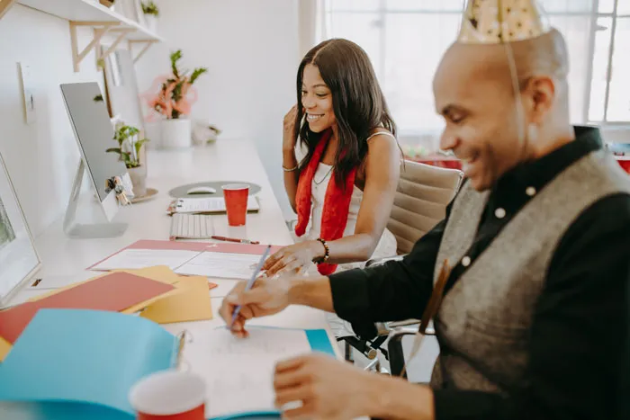 man in a party cap and woman smiling and working