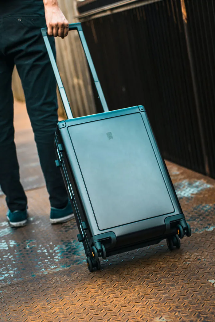 Person walking with a wheeled suitcase on a metal walkway, capturing travel plans for New Year’s Eve.