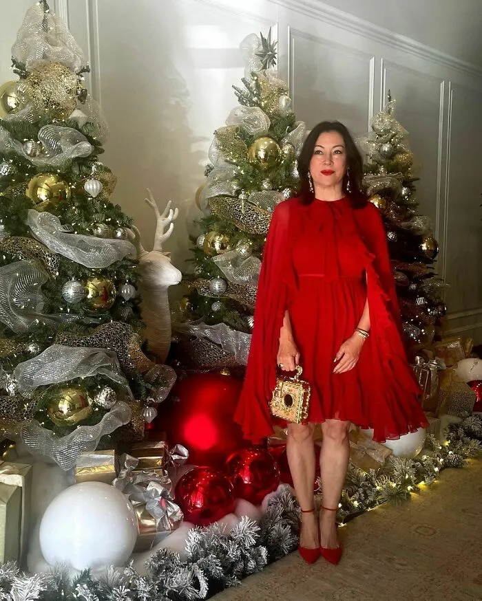 Woman in a red dress posing by decorated Christmas trees and festive ornaments featuring smartest celebrities intelligent theme.