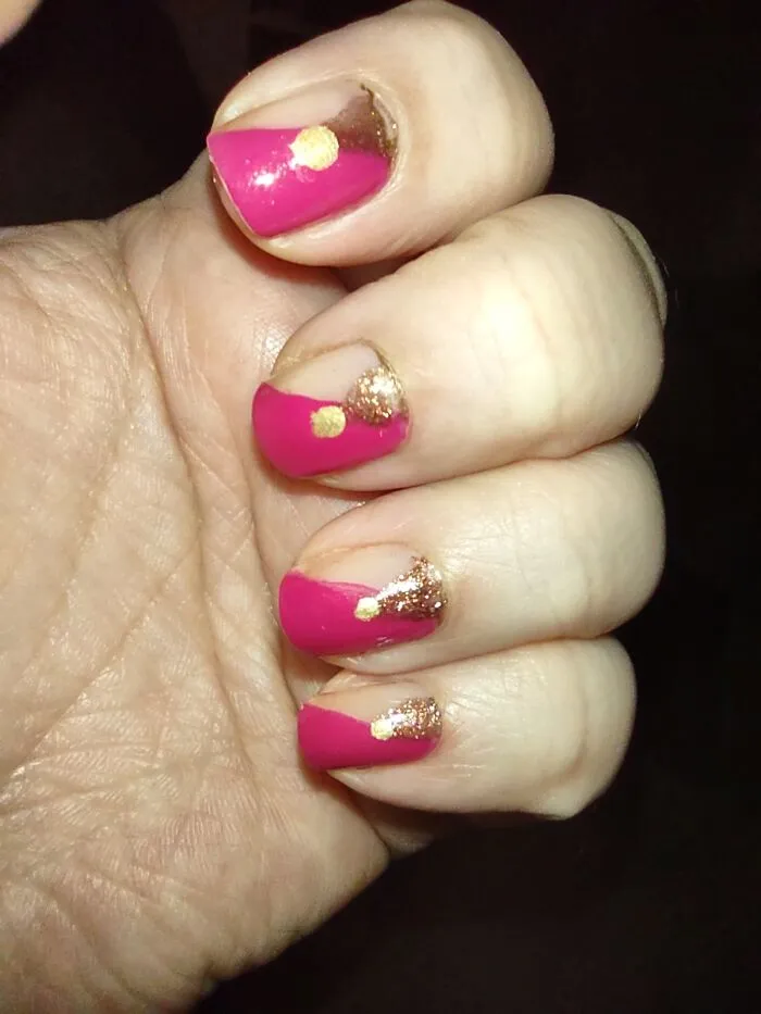 Close up of fingers featuring elegant pink and gold winter nail art designs