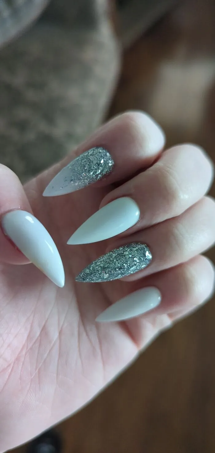 Elegant winter nail art design featuring long pointed light blue and silver glitter nails