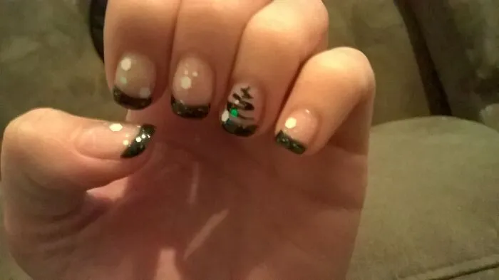 Minimalist winter nail art with black french tips and a small painted pine tree
