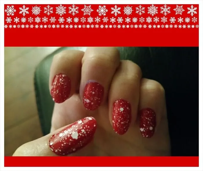 Red Christmas nail art with white speckled snow effect.