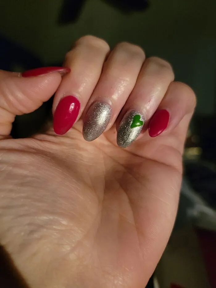 Simple winter nail art with red, silver, and a tiny green heart.