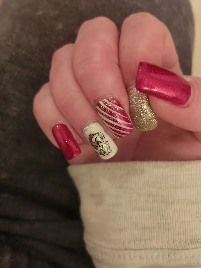 Festive Christmas nail art design with candy cane stripes and a cute holiday character on a hand