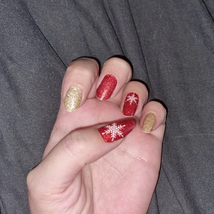 Glittering red and gold winter nail art with snowflake details.