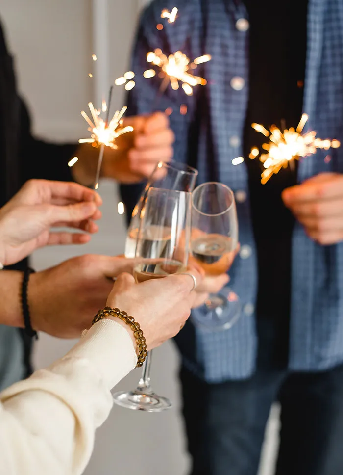 Persons holding Bengal flames and glass of Champagne
