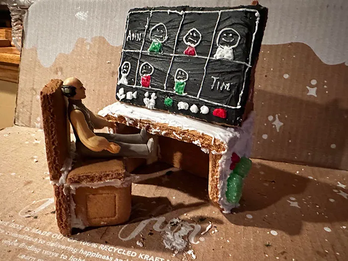 Gingerbread person at a cookie desk, attending a virtual meeting with humor-themed Christmas decorations.