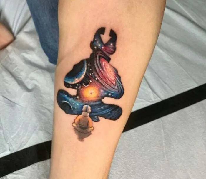 Colorful trippy tattoo of Avatar Aang meditating with a cosmic galaxy design on an arm.