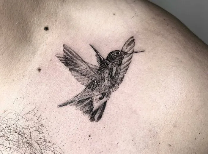 Trippy blurred bird tattoo on a man's chest, featuring a detailed avian design.