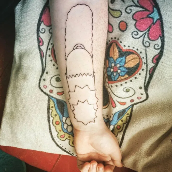 Arm with minimalist chainsaw tattoo on colorful fabric background.