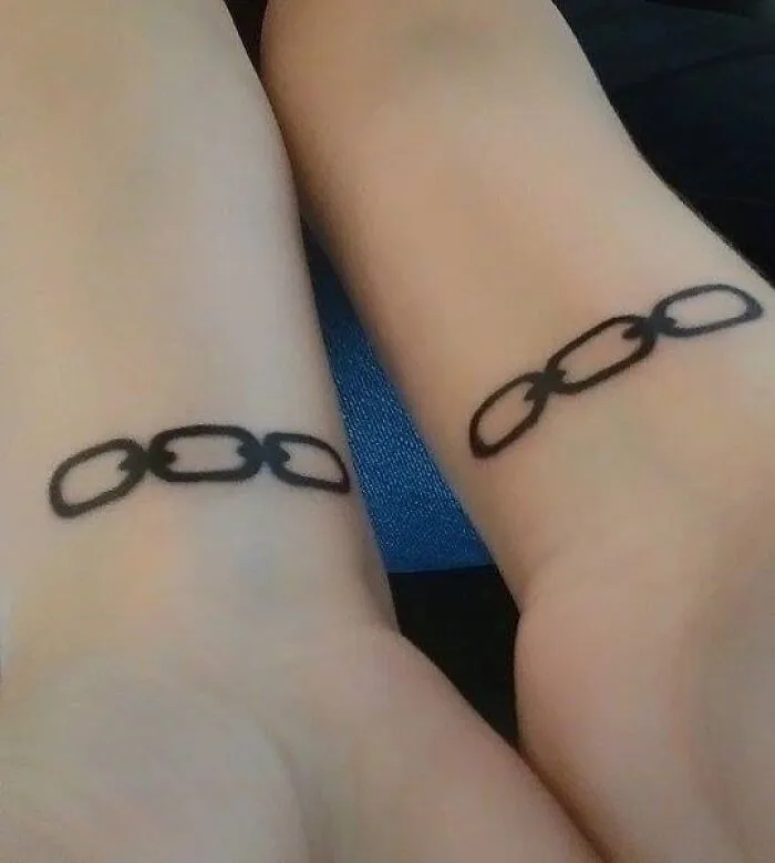Minimalist tattoos of linked chains on wrists, simple and aesthetically pleasing design.