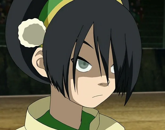 Female cartoon character with strength, dark hair and green outfit, showing determination.