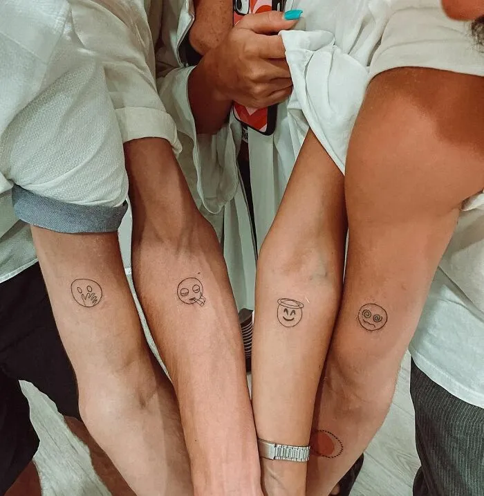 Minimalist tattoos of expressive faces on four arms, showcasing simple yet aesthetically pleasing designs.