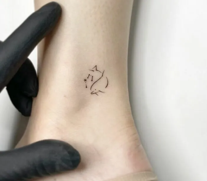 Minimalist tattoo of two dolphins on an ankle, highlighting simple and aesthetically pleasing design.