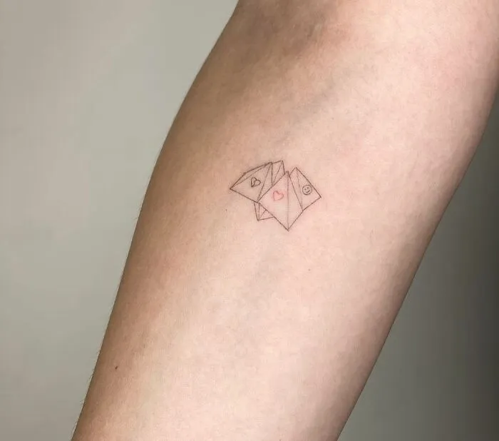 Minimalist tattoo of three small envelopes on forearm, featuring subtle heart and smiley face details.